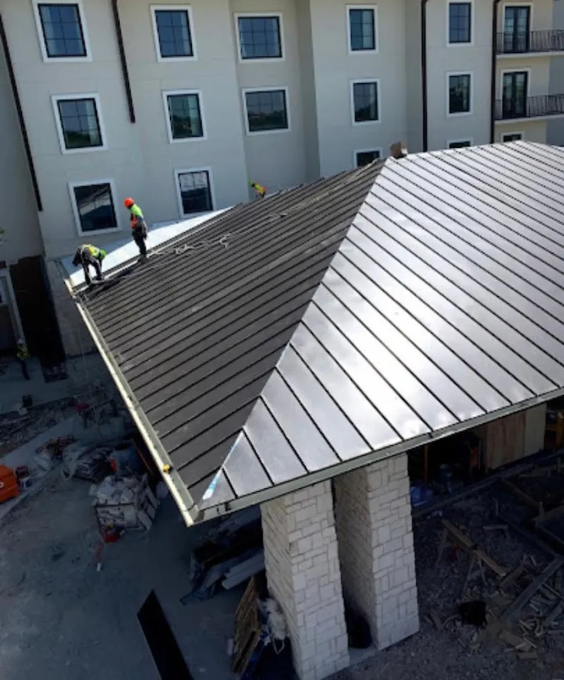 Crew installing standing seam metal roof panels on a commercial project in Clifton Park